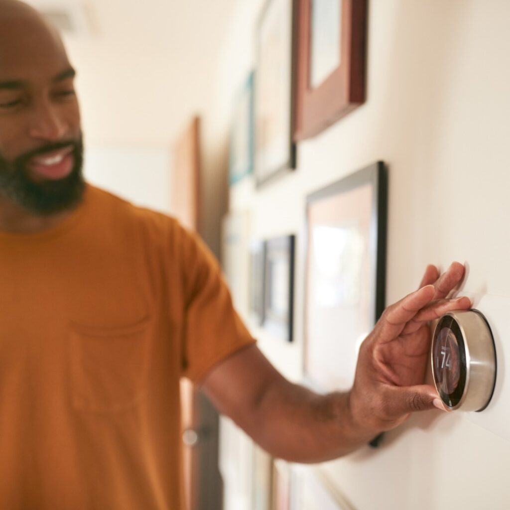 man adjusting thermostat