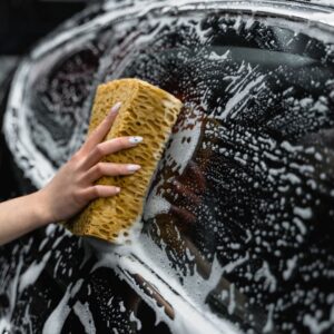 Close-up of a sponge washing a car window