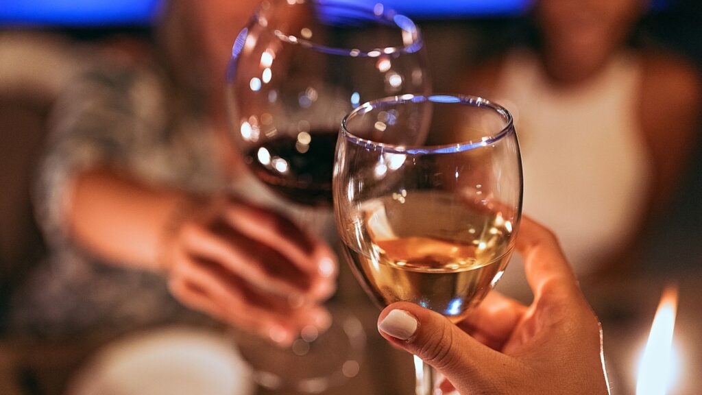 Close-up of two wine glasses clinking together