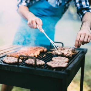 Someone grilling hamburgers and hotdogs