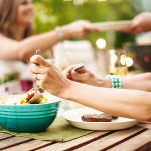 Close-up of someone stirring a summer salad at an outdoor table