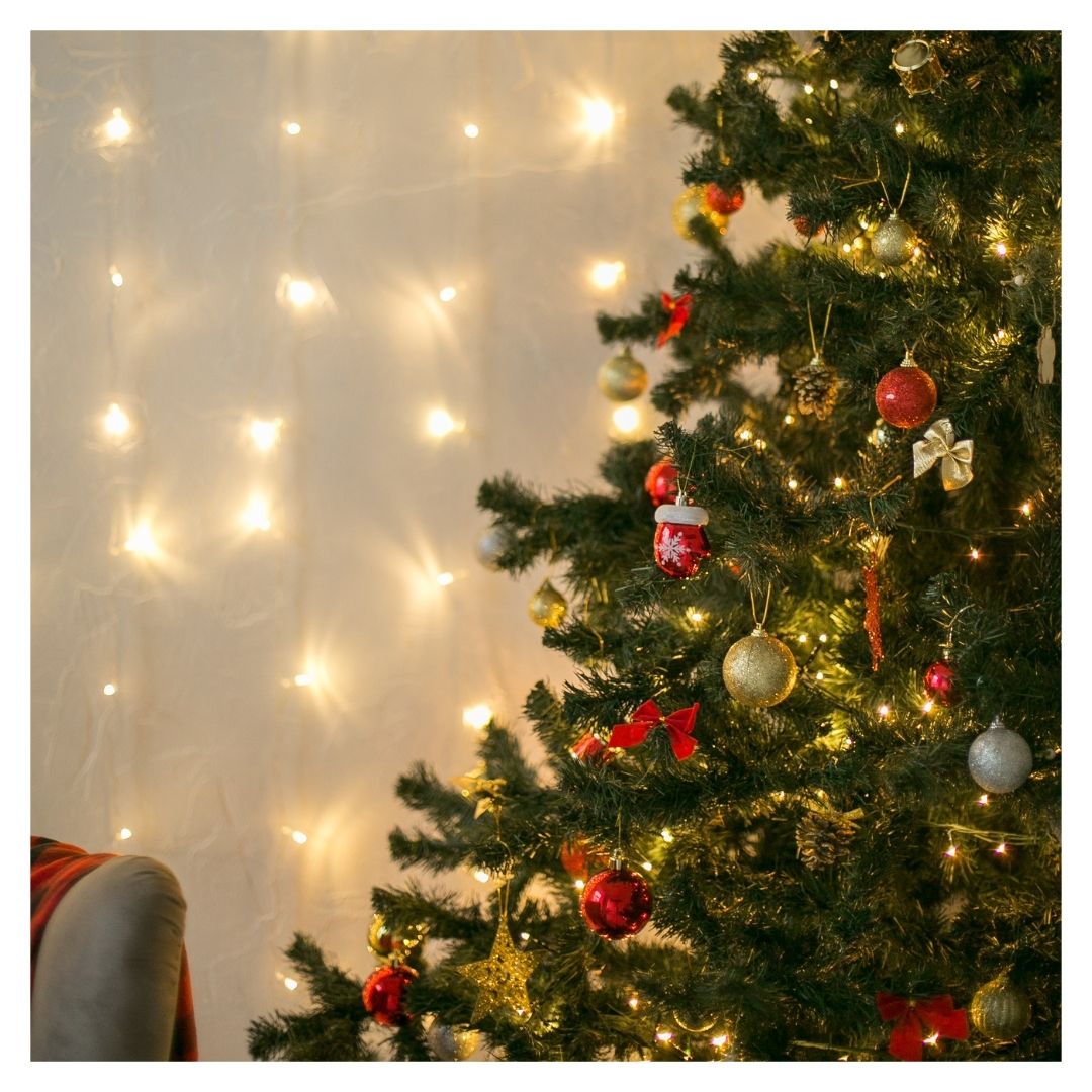 string lights on the wall next to a Christmas tree